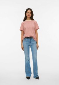 Rood-wit gestreept T-shirt met korte mouwen gecombineerd met lichtblauwe uitlopende spijkerbroek. De outfit is voorzien van een zwarte riem en puntige zwarte schoenen.