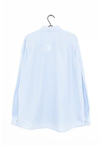 Camicia a quadri blu chiaro in tessuto, con maniche lunghe, colletto classico e polsini con bottone. Appesa a un gancio nero.