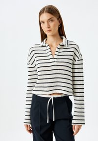 Gestreepte gebreide pullover in crèmekleur en marineblauw, met een kraaglijn en lange mouwen. Cropped ontwerp met geribbelde textuur en open zijkanten.