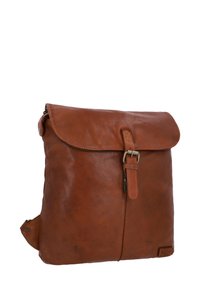 Zaino in pelle marrone con chiusura a pattina, dettaglio con fibbia e texture liscia. Presenta una cerniera laterale e un branding sottile nella parte inferiore.