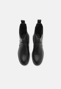 Bottes de cheville en cuir noir avec une finition lisse, panneaux latéraux élastiques et clous en argent le long de la tige. Bout rond et semelle plate.