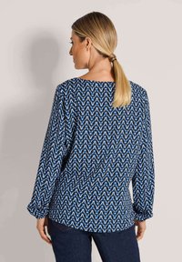 Blue and white patterned long-sleeve blouse with a boat neckline, featuring a loose fit and gathered sleeves, made of lightweight fabric.