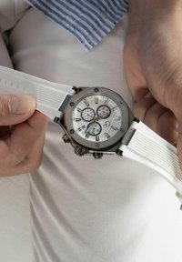 Orologio con cinturino in gomma bianca, cassa metallica argentata, quadrante rotondo, cronografi e quadrante bianco testurizzato con accenti scuri.