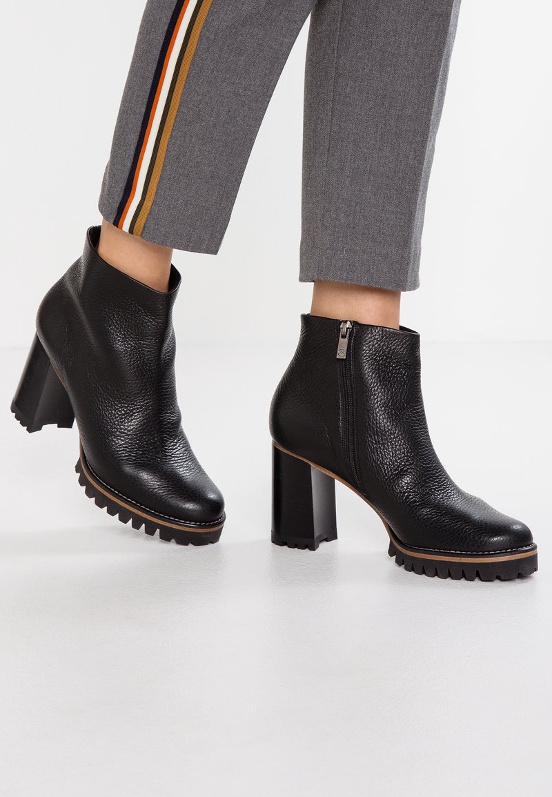 Bottes d"imitation cuir noires à la cheville avec finition texturée, talon carré haut et semelle en caoutchouc. Dotées d"une fermeture éclair latérale.