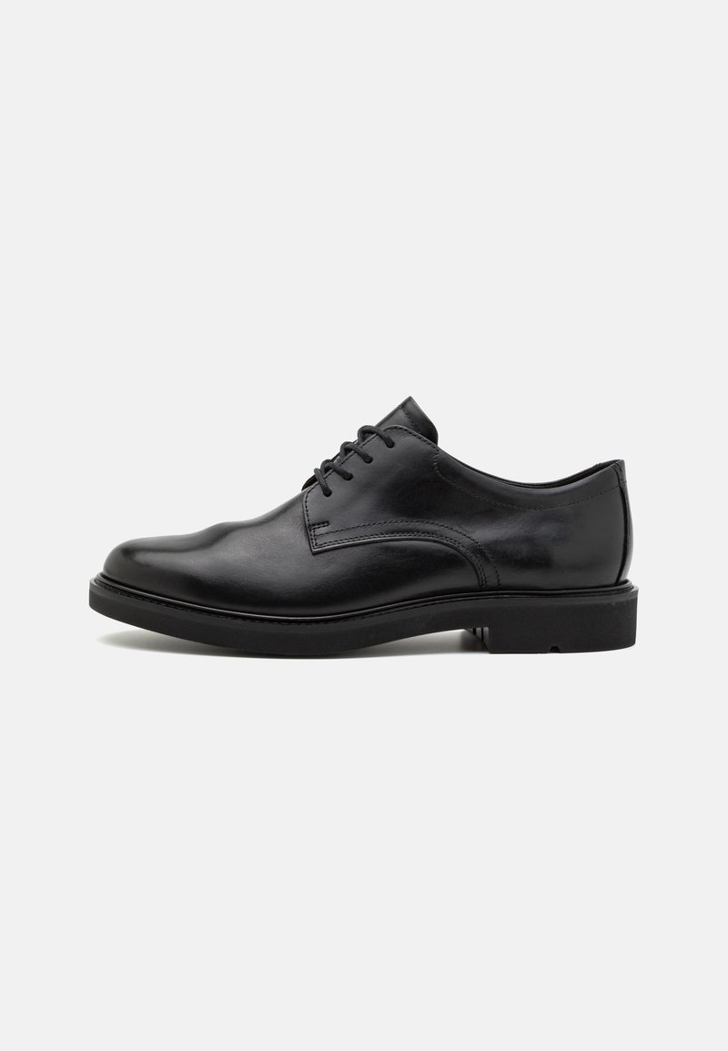 Chaussure de ville classique noire en cuir pour homme avec un laçage et des détails cousus sur une semelle en caoutchouc plate, vue de côté.