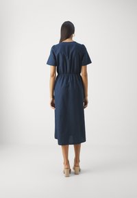 Navyblaues Leinenkleid mit kurzen Puffärmel, elastischem Bund und knielanger Länge. Glatte Textur, minimalistisches Design und keine sichtbaren Muster.