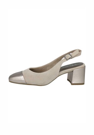 Zapato de ante beige con tiras al tobillo y puntera metálica plateada, con un tacón cuadrado. Correa ajustable en el tobillo con detalle de hebilla.