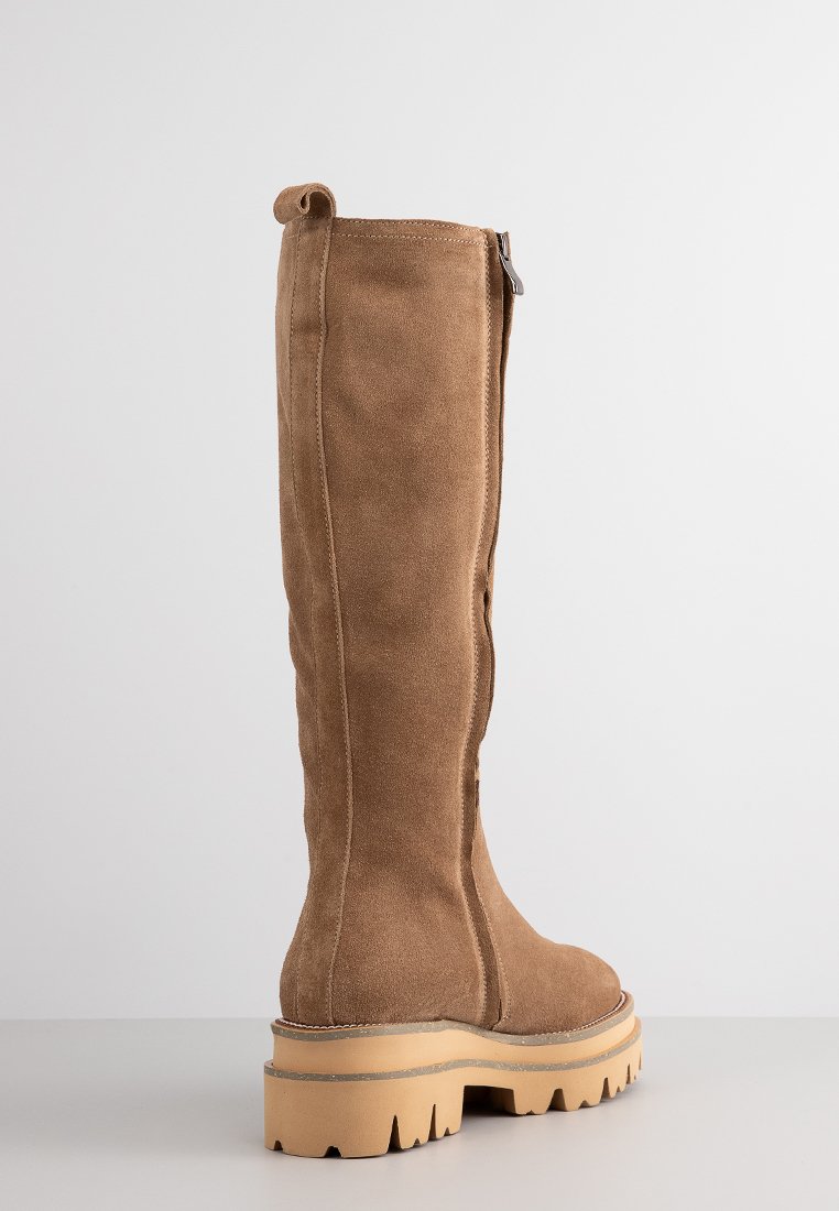 Braune Wildleder-Stiefel in Knielänge mit dickem Profilsohle und seitlichem Reißverschluss, von hinten vor einem schlichten hellen Hintergrund angezeigt.