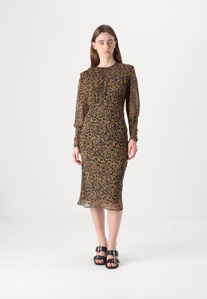 Sheer, long-sleeved dress in a black and golden leopard pattern, with a fitted silhouette and a below-knee hem. Paired with black buckle sandals.