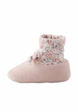 Soft pink baby shoe with ribbed texture and a floral fabric cuff tied with a small bow around the ankle.