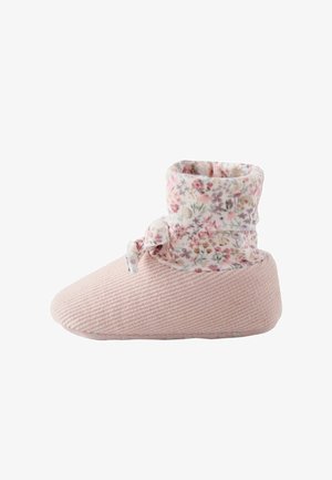 Soft pink baby shoe with ribbed texture and a floral fabric cuff tied with a small bow around the ankle.