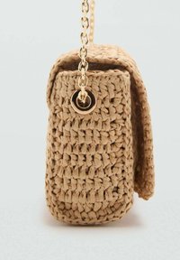 Woven beige crossbody bag with a textured surface, featuring a gold chain strap and a circular hardware accent on the side.