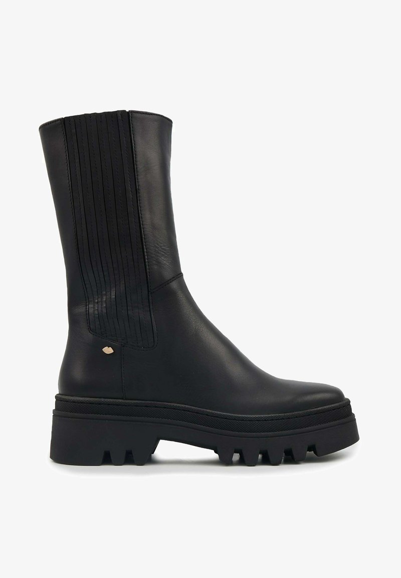 Bottines en cuir noir avec un design à panneaux côtelés, semelle épaisse avec des rainures profondes et un petit accent métallique sur le côté.