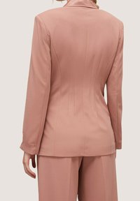 Dopasowana różowa marynarka o gładkiej fakturze, z wyciętym kołnierzem, dopasowanym tyłem i pionowymi szwami.