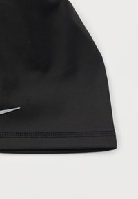 Casquette de sport noire en matériau élastique avec une texture lisse. Dispose d'un ourlet cousu et d'un logo argenté sur le devant.