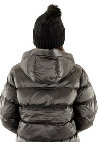 Chaqueta de plumas negra con capucha, con un acabado brillante y patrón de costura horizontal. Combinada con un gorro de punto negro con pompón.