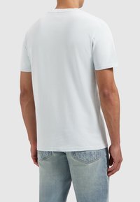 Lichtblauwe katoenen t-shirt met korte mouwen, ronde hals en een casual pasvorm. De stof lijkt zacht met een gladde textuur.