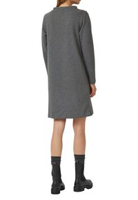 Grijze gebreide jurk met lange mouwen, een ronde halslijn en zijslits; gedragen met zwarte enkellaarzen en gestructureerde grijze sokken.