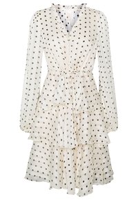 Vestido blanco en capas con lunares negros; escote en forma de V, mangas largas y volantes en las capas. Hecho de una tela ligera y transparente.