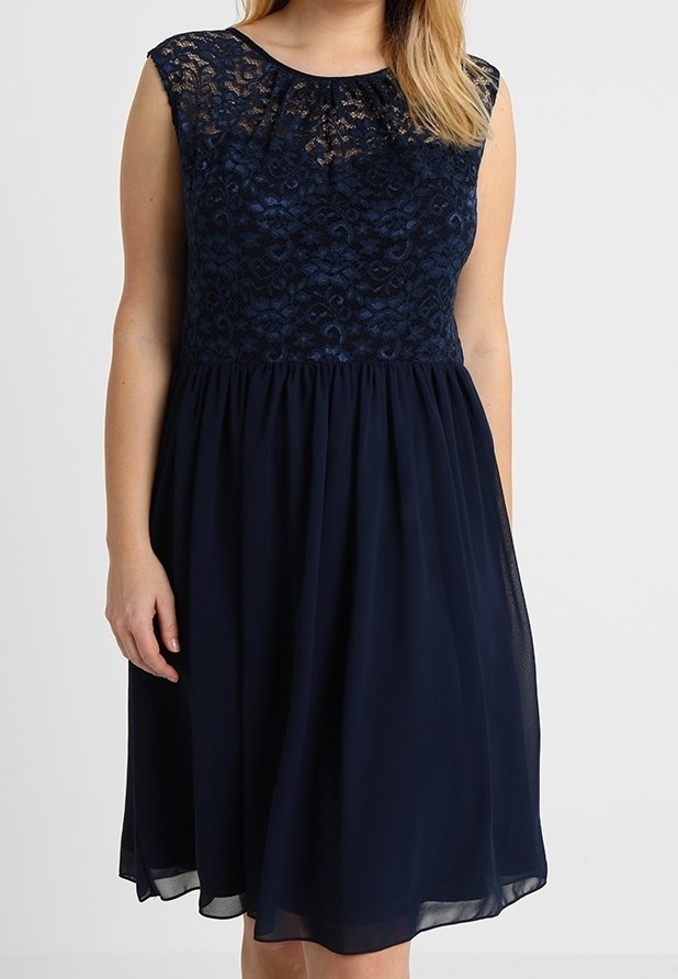 Robe bleu marine avec un corsage en dentelle, design sans manches, encolure ronde et jupe en chiffon fluide. Présente un revêtement texturé et une taille froncée.