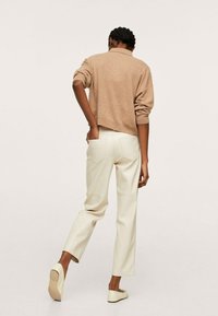 Jasnobrązowy krótki sweter, kremowe spodnie z wysokim stanem i beżowe baleriny. Prosty design z miękką teksturą. Widok z tyłu, z delikatnymi detalami na kieszeniach.