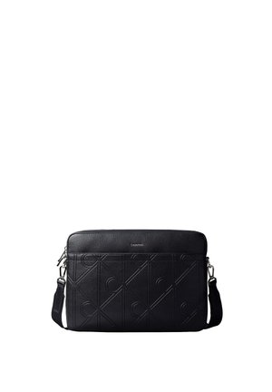 Borsa a tracolla in pelle nera con motivo "CK" in rilievo, fibbie argentate e tracolla regolabile, progettata per trasportare laptop o documenti.