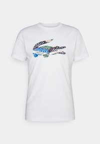 White cotton T-shirt featuring a graphic design of overlapping text and logos in various colors, including blue, green, and red.