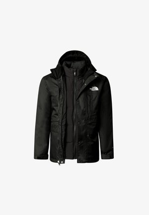 Chaqueta impermeable negra con capucha, sudadera gris, pantalones negros y zapatos negros. Mochila amarilla, gafas de sol grises y acentos de logo visibles.