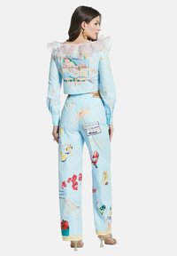 Light blue two-piece outfit with a ruffled collar, featuring vibrant beach-themed prints and accents, made of soft fabric.