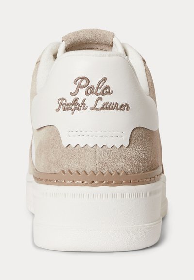 Beigeä mokkaa ja valkoista nahkaa oleva tennarin kanta, jossa "Polo Ralph Lauren" on kirjailtu beigen värisellä langalla takalenkkiin valkoisen pohjan yläpuolelle.