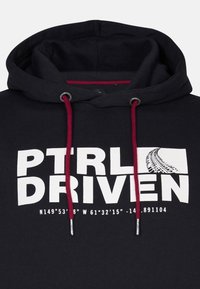 Čierna mikina s kapucňou so bielou grafickou potlačou a textom "PTRLD DRIVEN" a súradnicami, doplnená burgundskými šnúrkami a strieborným kovaním.