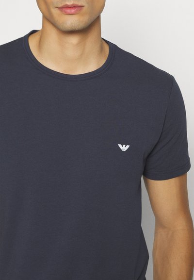 Navy blue short-sleeve T-shirt made of cotton with a round neckline. Features a small white logo on the left chest. Soft, smooth texture.