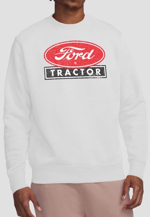 Weißer Pullover mit rotem ovalem "Ford"-Logo über einem schwarzen Rechteck mit dem weißen Schriftzug "TRACTOR", getragen von einer Person.