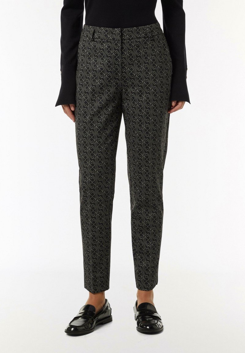 Black and patterned trousers featuring a geometric design in olive green, tailored fit, smooth fabric, and ankle-length cut.