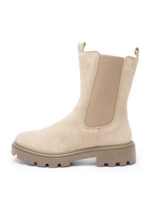 Bottine beige en daim avec semelle crantée épaisse, panneau latéral élastique et languettes à l'arrière et à l'avant pour faciliter l'enfilage.