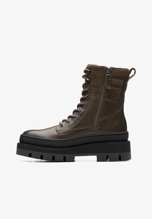 Brown leather ankle boots featuring a lace-up front, side zipper, and a chunky black sole with deep grooves for traction.