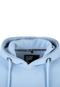 Sudadera azul claro con capucha ajustable, textura suave y una etiqueta en el interior que muestra el nombre de la marca, el año de establecimiento y la información de la talla.
