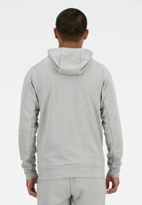 Felpa grigia con una vestibilità comoda, realizzata in tessuto morbido. Presenta un cappuccio con coulisse e polsini a coste, con una texture liscia e un design semplice.