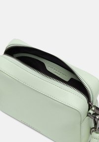 Mintgrünes Lederhandtasche mit einem Reißverschluss oben, ausgestattet mit einem schwarzen Innenfutter. Enthält silberne Hardware und geprägtes Branding an der Seite.