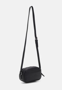 Czarna skórzana torba na ramię o zaokrąglonym kształcie, zamykana na zamek błyskawiczny, z regulowanym paskiem zapewniającym wygodne noszenie. Gładka faktura, minimalne detale.