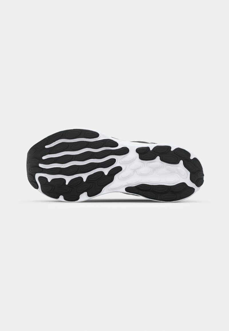 Suela de zapatilla en blanco y negro que muestra una suela de goma texturizada con surcos curvados y patrones de tracción distintos para un mejor agarre.