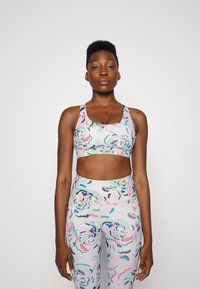 Conjunto de roupa desportiva com padrão floral em cores pastel. O sutiã desportivo possui uma banda larga e decote arredondado, complementado por leggings de cintura alta.