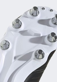 Sort fodboldsko sål med metalliske studs og et tekstureret hvidt design, der inkluderer vinklede riller og afrundede accenter.