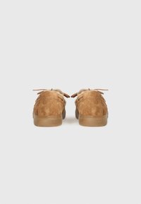 Een paar bruine suède veterschoenen met een beige bontvoering, gezien vanuit de achterkant op een effen witte achtergrond.