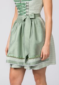 Light green dress with a fitted bodice, lace-up front, and a gathered skirt, featuring decorative trims and a matching bow at the waist.