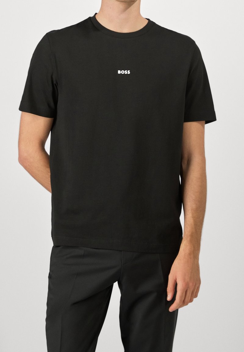 Černé bavlněné tričko s krátkým rukávem. Na hrudi se nachází malé bílé logo "BOSS". Kulatý výstřih, volný střih, hladká textura.