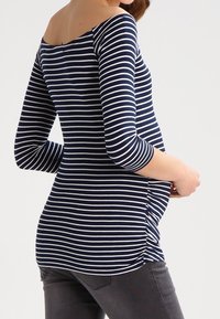 Marineblau-weiß gestreifte Umstandbluse mit schulterfreiem Ausschnitt, drei Viertelärmeln, seitlicher Raffung und slim Fit.
