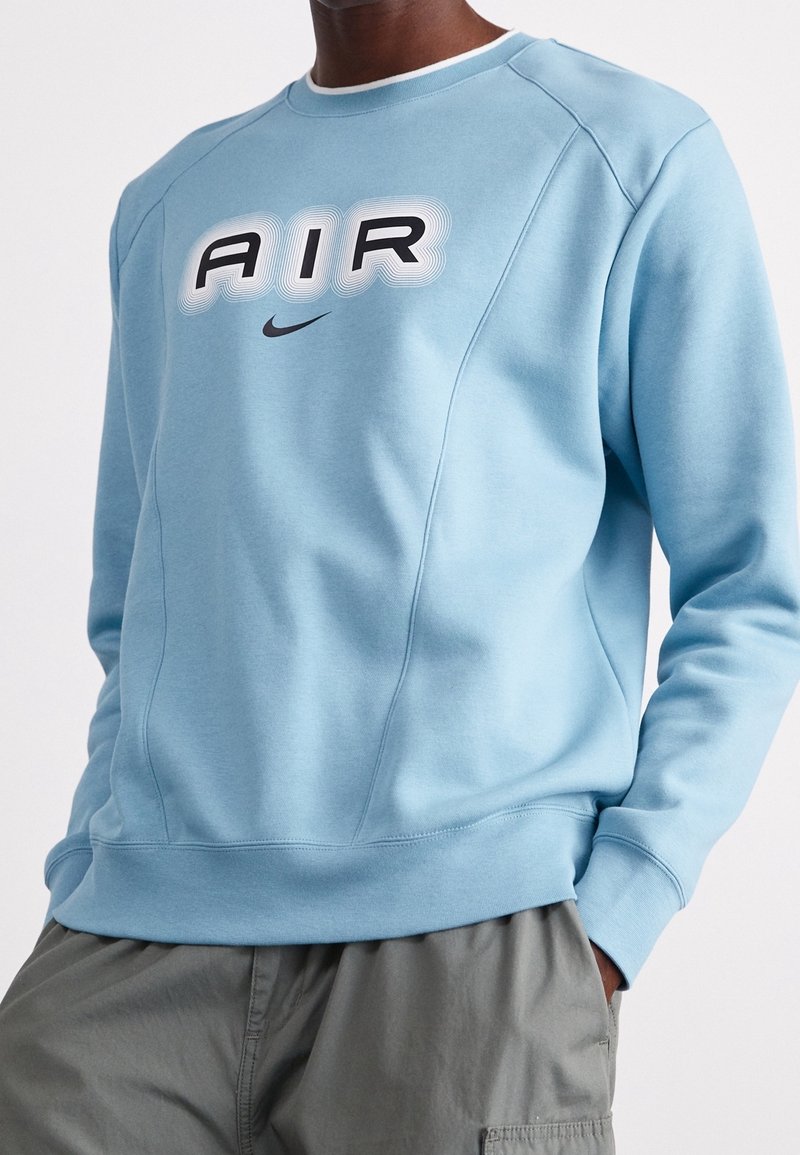 Ljusblå sweatshirt med rund hals, utrustad med en framträdande "AIR" grafik i svart och grått. Tillverkad av mjukt material med ribbade ärmslut.
