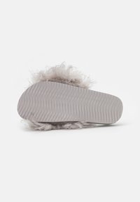 Fluffy gray slipper with a thick, textured sole. The bottom features a wavy pattern, providing grip and stability. Soft material for comfort.