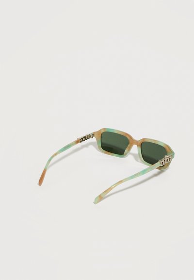 Lunettes de soleil rectangulaires avec verres verts et montures marbrées vertes et brun clair, posées ouvertes sur une surface blanche.